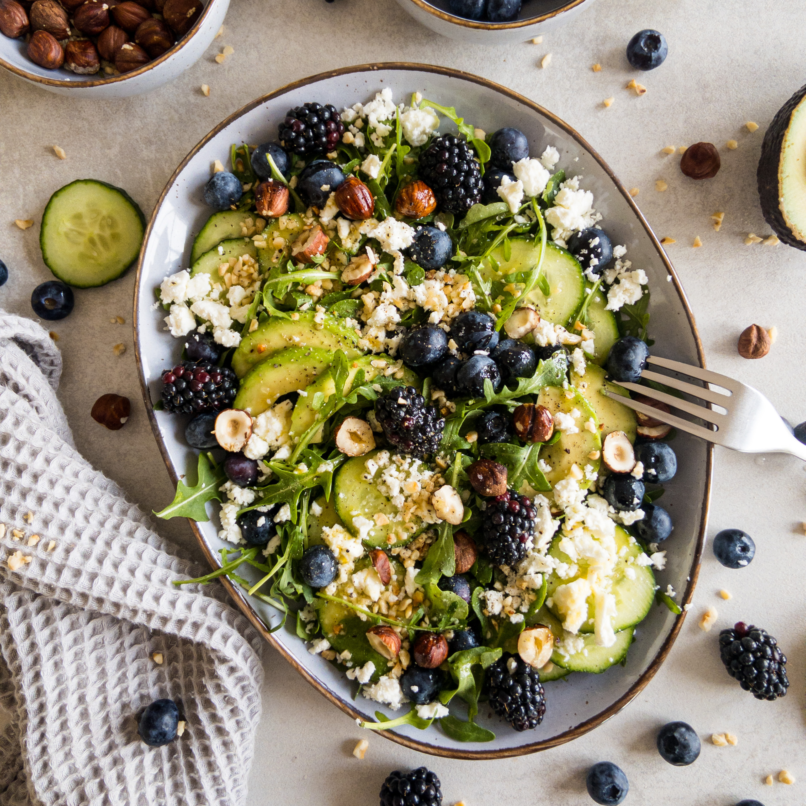 Leichter Avocado-Rucola Salat mit Beeren auf einem Teller - ideal für den Sommer.