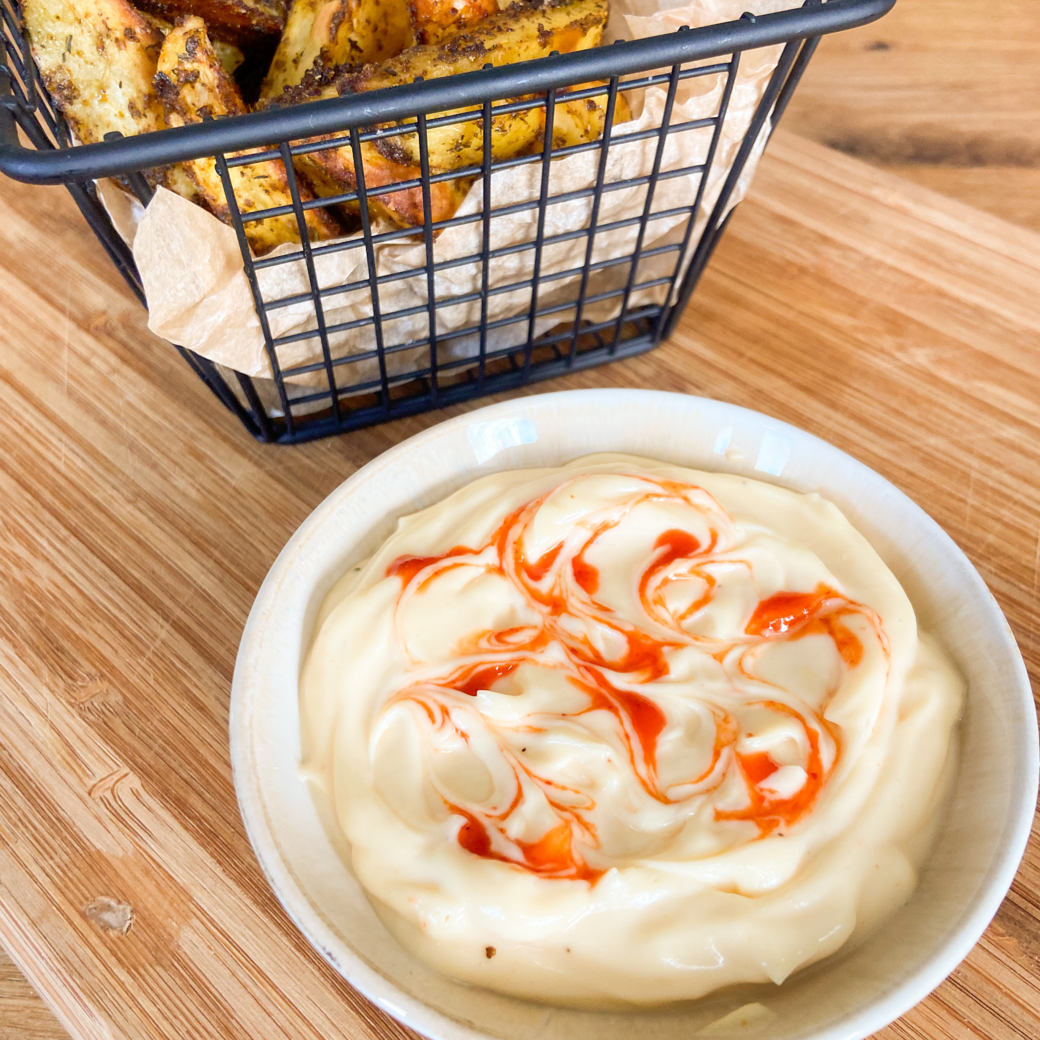 Chil-Mayonnaise im Schälchen. Im Hintergrund Korb mit leckerem Kräuterbrot.