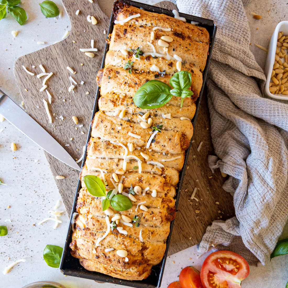 Faltenbrot Tomate-Mozzarella in Backform auf einem Brettchen.