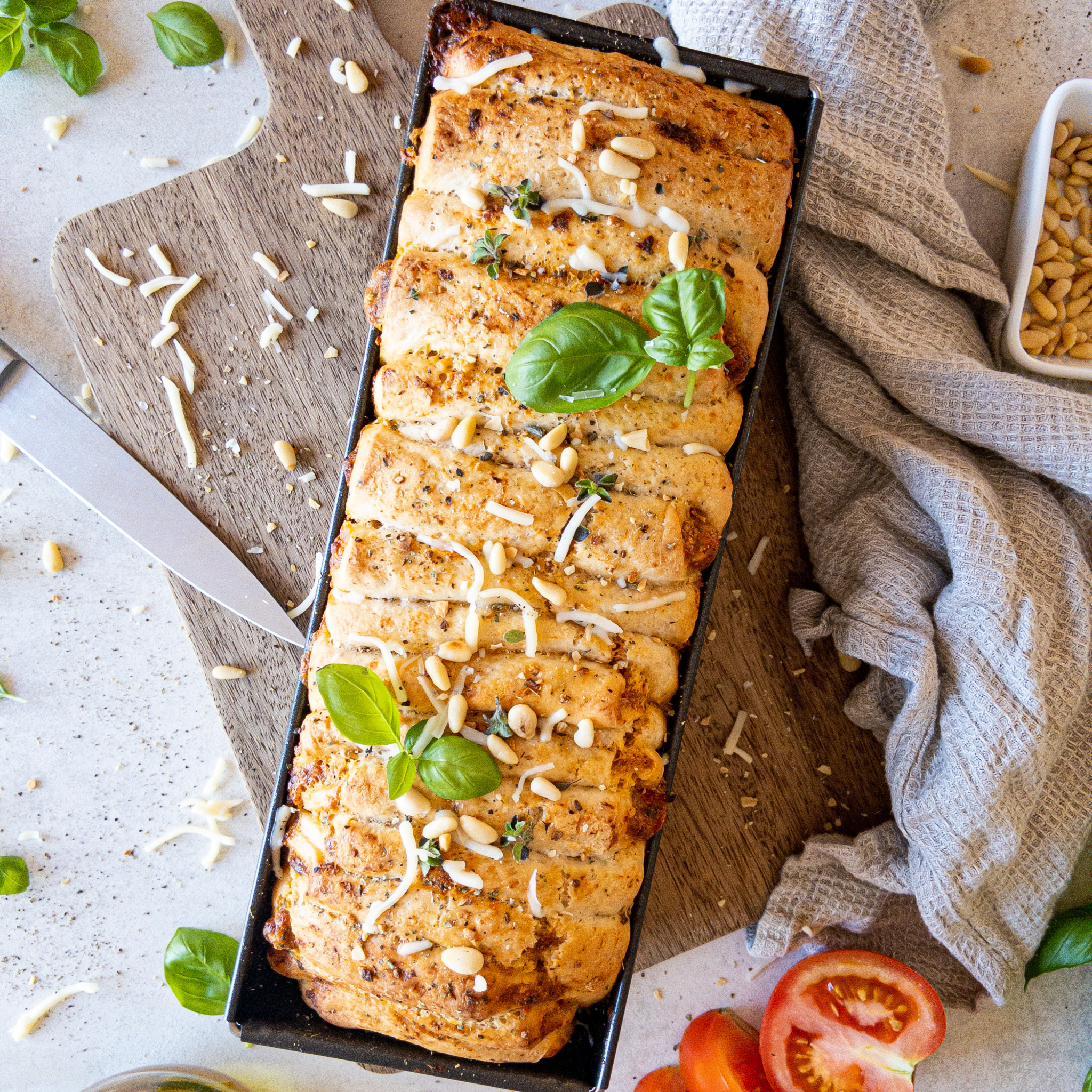 Faltenbrot Tomate-Mozzarella in Backform auf einem Brettchen.
