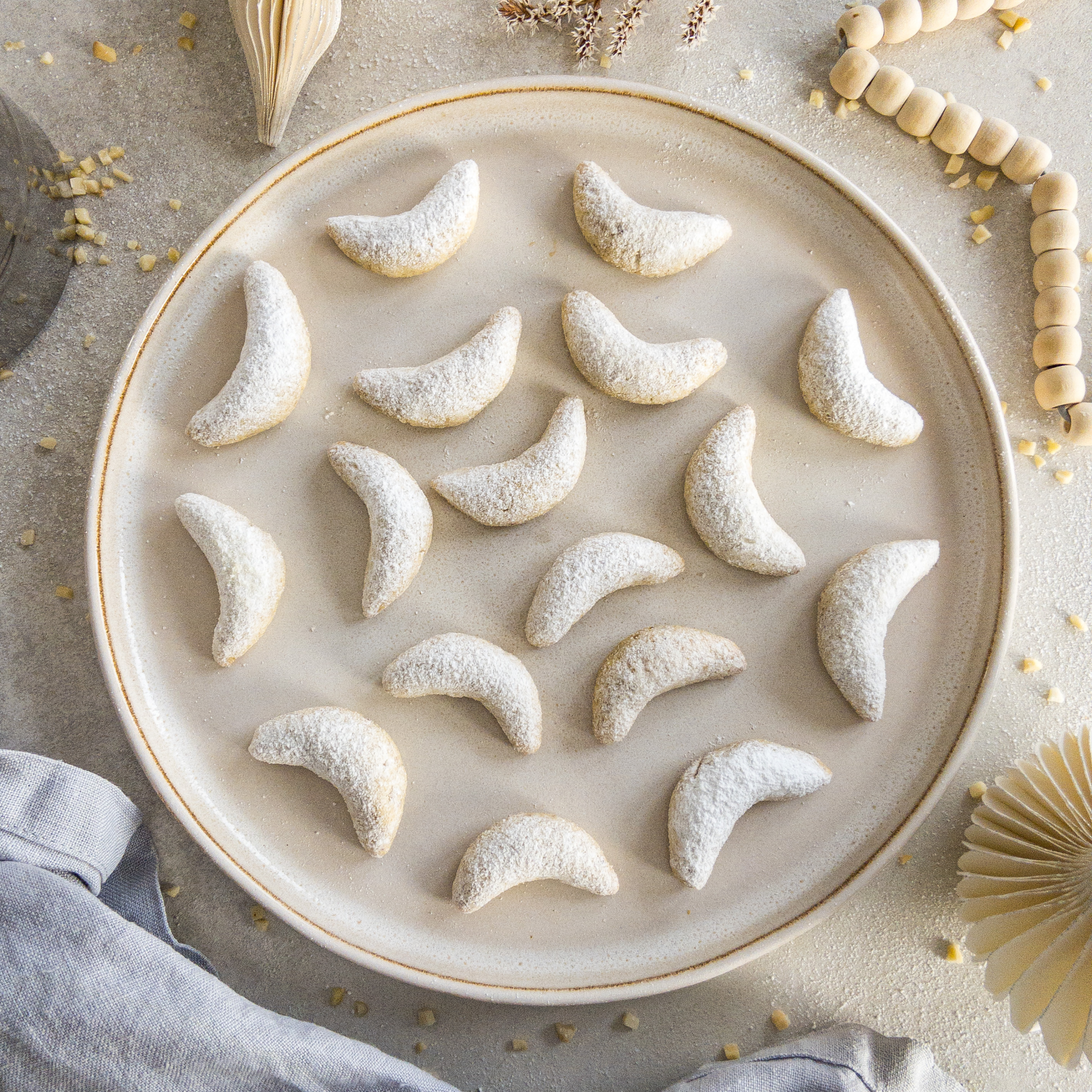 Vanillekipferl auf einem runden beigen Steingut-Teller.