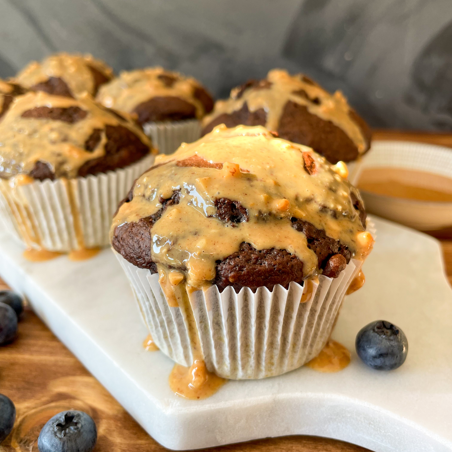 Schokomuffins mit Nussmus überzogen auf einem weißen Brettchen.