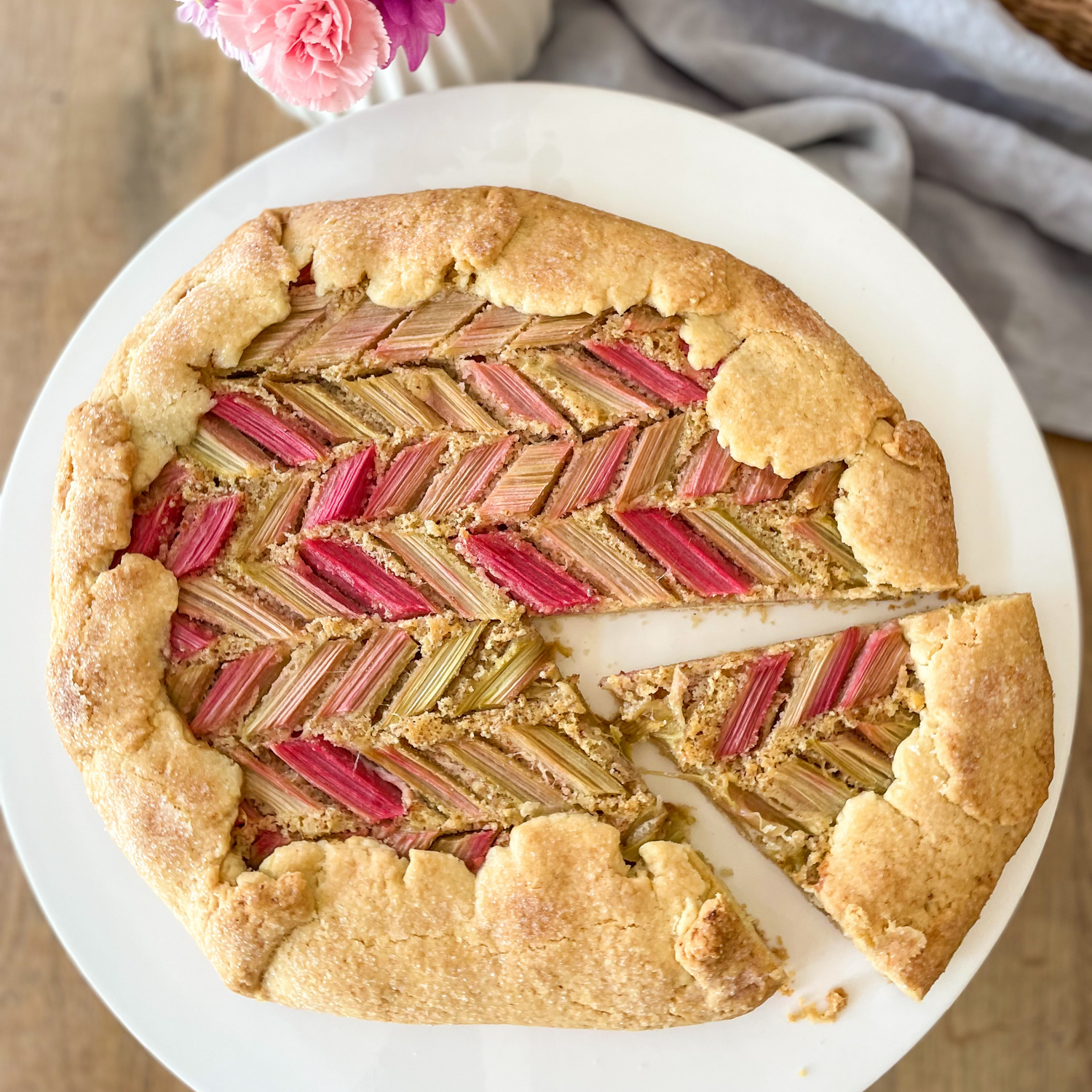 Angeschnittene Rhabarber Galette auf weißem Teller.
