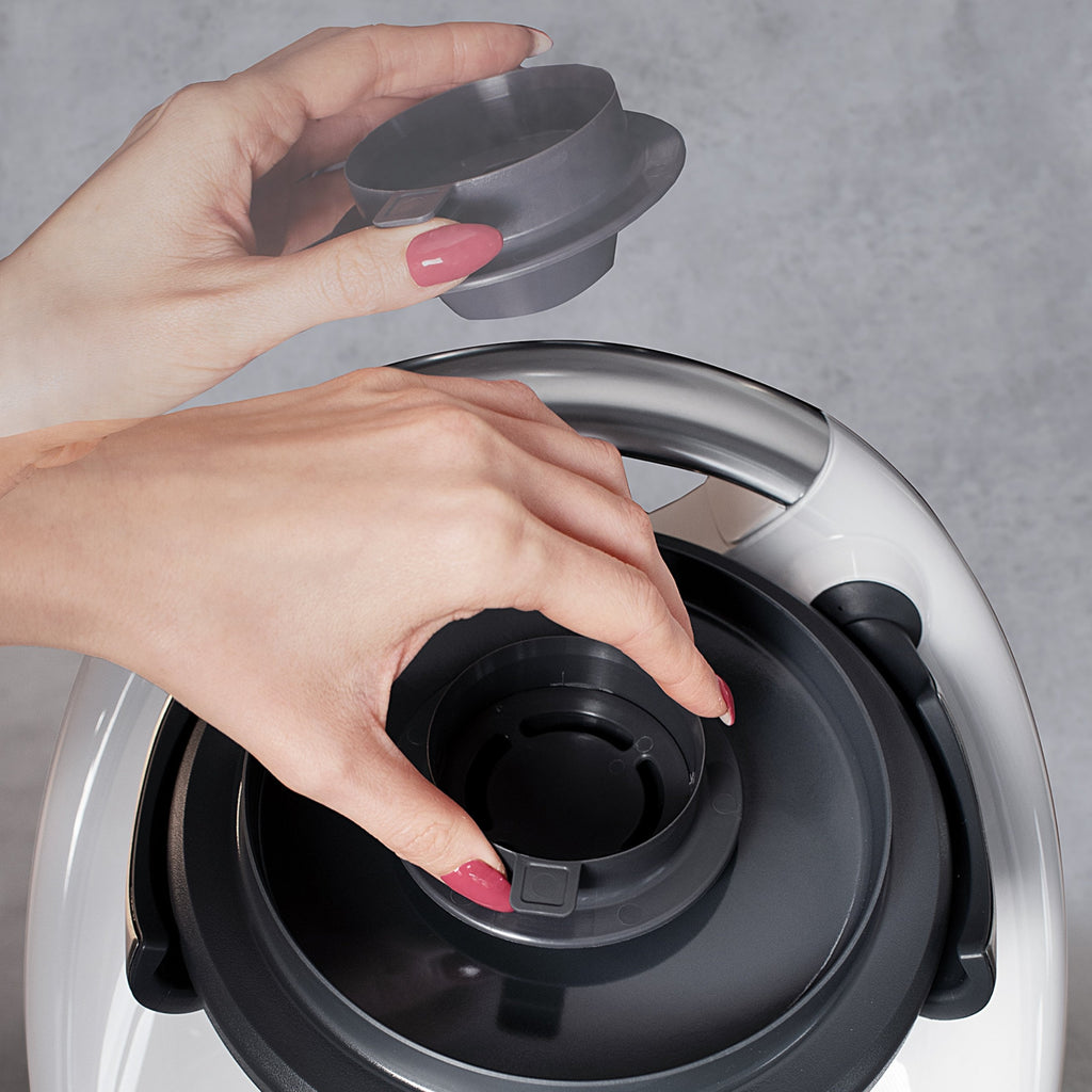 Spritzschut-Aufsatz SplashPro wird von einer Hand auf Thermomix gelegt.